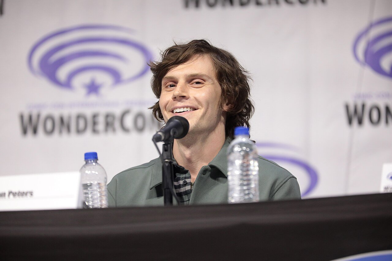 Evan Peters sourit devant un micro