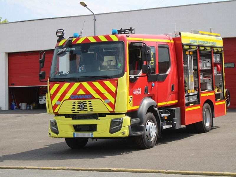 Un camion de pompiers rouge et jaune devant une caserne