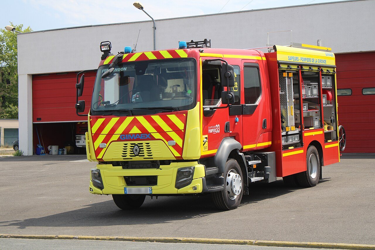 Un camion de pompiers rouge et jaune devant une caserne