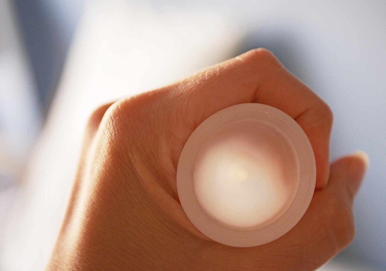 Une main tient une coupe menstruelle