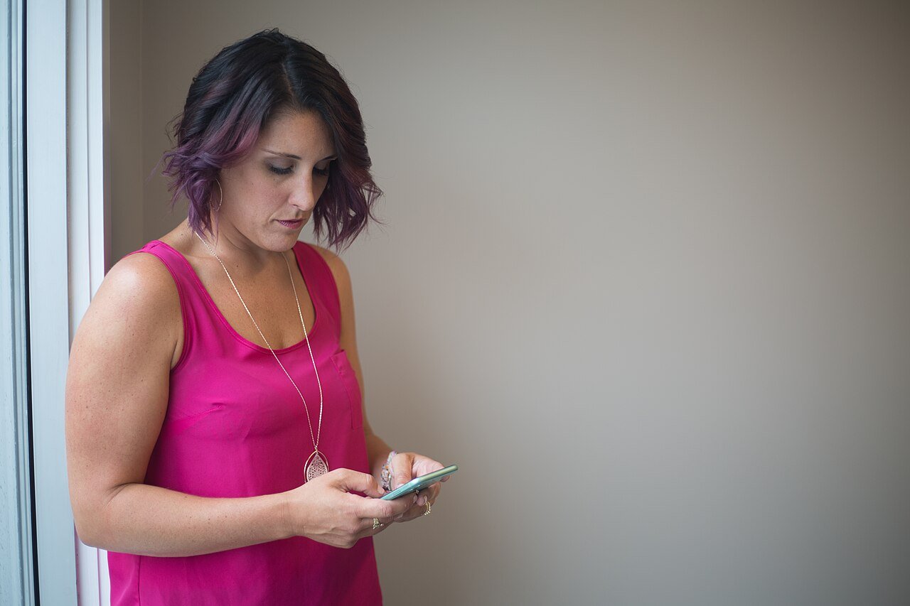 Une femme de profil regarde son téléphone